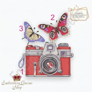 May include: A red vintage camera with a silver lens and two butterflies, one red and one blue, flying around it. The camera has a silver strap and a silver top. The butterflies are both in flight and have their wings spread out. The image is a digital embroidery design.