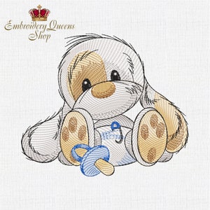 May include: Embroidered design of a cute, light brown and white puppy sitting with a blue pacifier. The puppy has a brown nose and black eyes.