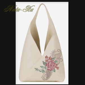 K&ouml;nnte beinhalten: Eine beige Canvas-Tragetasche mit einem floralen Stickmuster, das eine rosa Rose, gr&uuml;ne Bl&auml;tter und ein Paisley-Muster zeigt.