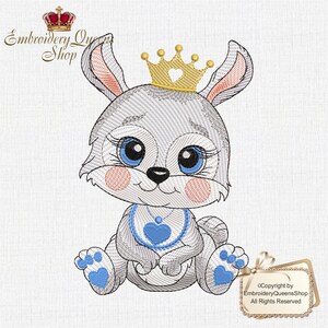 May include: An embroidered design of a baby rabbit wearing a gold crown with a heart cutout. The rabbit has blue eyes, pink cheeks, and a blue bib with a heart. Design by Embroidery Queen Shop.