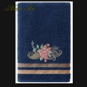 K&ouml;nnte beinhalten: Ein dunkelblaues Badetuch mit einem floralen Stickmuster. Die Stickerei zeigt eine rosa Rose mit gr&uuml;nen Bl&auml;ttern und einem Paisley-Muster.