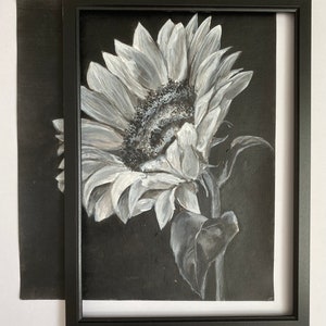 May include: A black and white painting of a sunflower against a dark background. The sunflower is in focus and the background is blurred.