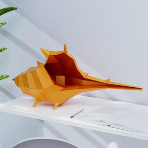 Puede incluir: Un escritorio blanco con una silla blanca y una gran escultura de concha naranja en la parte superior. El escritorio tiene una superficie blanca y un marco de metal blanco. La silla es una silla blanca de estilo Eames con patas de madera. La escultura de concha está hecha de papel y tiene la forma de una concha.