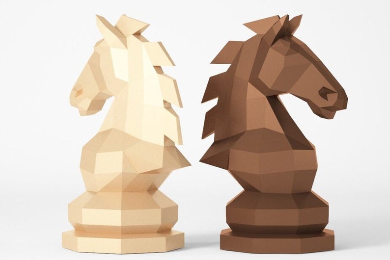 Puede incluir: Dos piezas de ajedrez de origami, un caballo blanco y un caballo marr&oacute;n, se muestran lado a lado. Los caballos est&aacute;n hechos de papel y tienen un dise&ntilde;o geom&eacute;trico.