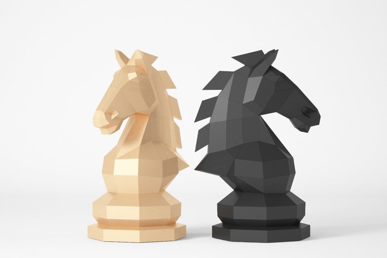 Puede incluir: Dos piezas de ajedrez, un caballo negro y un caballo dorado, est&aacute;n colocados uno al lado del otro. Los caballos est&aacute;n hechos de un material de papel texturizado y est&aacute;n mirando en direcciones opuestas.