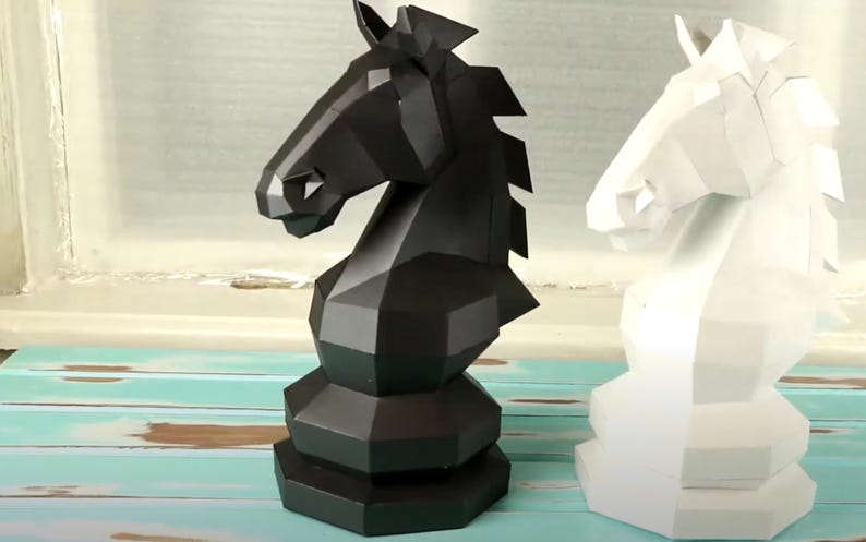 Puede incluir: Dos piezas de ajedrez, un caballo negro y un caballo blanco, est&aacute;n hechos en un estilo geom&eacute;trico y angular. Las piezas est&aacute;n hechas de un material s&oacute;lido y opaco.