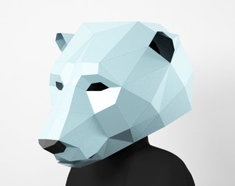 Peut inclure: Un masque de papier en forme d'ours polaire bleu clair. Le masque est fait de papier plié et a un design géométrique. Le masque est conçu pour être porté sur la tête.