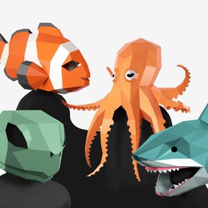 May include: A whimsical illustration features four geometric animal masks: an orange and white clownfish, an orange octopus, a green alien, and a blue shark with an open mouth. The masks are set against a black background.
