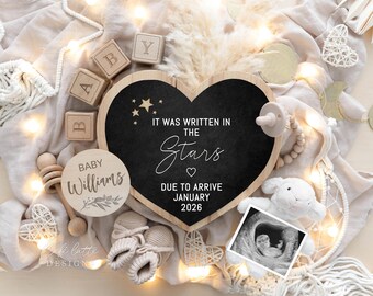 Peut inclure: Tableau noir en forme de cœur avec le texte "IT WAS WRITTEN IN THE STARS" et "DUE TO ARRIVE JANUARY 2026". L'image comprend des blocs pour bébé, un hochet en bois, des chaussons et une échographie. Une annonce de bébé.