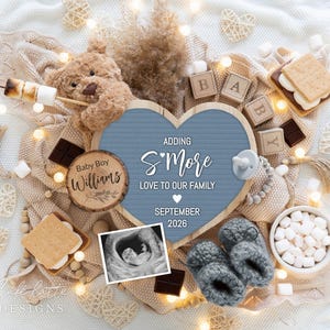 May include: A baby announcement with a blue heart-shaped sign that reads "Adding S'More Love to Our Family, September 2026." The image includes a teddy bear, baby booties, a sonogram, wooden blocks, s'mores, and marshmallows.