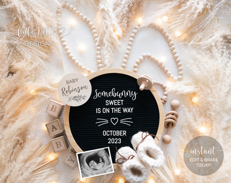 Puede incluir: Un tablero de letras negro con el texto "Somebunny Sweet is on the way" y la fecha "October 2023". Hay un peque&ntilde;o letrero de madera con el texto "Baby Robinson" y una imagen de ultrasonido en blanco y negro. El fondo es una superficie marr&oacute;n claro con luces blancas y hierba de pampa beige.