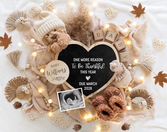 Peut inclure: Annonce de grossesse avec un ours en peluche portant un bonnet en tricot, entouré d'articles pour bébés. Un tableau noir en forme de cœur indique "One More Reason To Be Thankful This Year, Due March 2026." Comprend une échographie, des blocs et des chaussons tricotés.