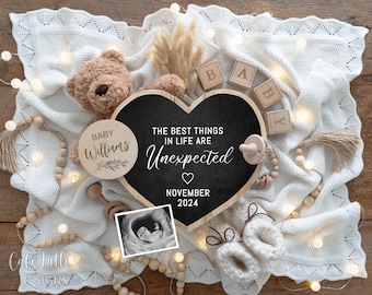 May include: A heart-shaped chalkboard sign with the text "The best things in life are unexpected" and "November 2024". The sign is surrounded by a white blanket, a teddy bear, wooden blocks spelling "BABY", a wooden circle with the text "Baby Williams", a wooden bead garland, and a baby's ultrasound image.