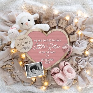 以下が含まれることがあります： ピンクのハート型の木製看板に「We are excited to say a Little Sister is on the way!」「September 2025」の文字が書かれています。小さな木製看板には「Baby Girl Williams」の文字が書かれており、小さな超音波画像があります。看板は白い毛布、木製のブロック、ぬいぐるみ、電球の列で囲まれています。