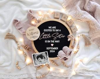 May include: A black letter board with the text "We are excited to say a little sister is on the way!" and the date "September 2024". There is a small ultrasound image, a wooden baby rattle, a pair of pink baby booties, and a wooden circle with the text "Baby Williams" on it.