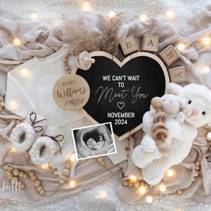 May include: A heart-shaped chalkboard sign with the text "We can't wait to meet you" and "November 2024".  A wooden circle with the text "Baby Williams" is also in the image.  The image includes a white knitted baby outfit, a pair of white booties, a white stuffed lamb, a wooden rattle, and a sonogram photo.