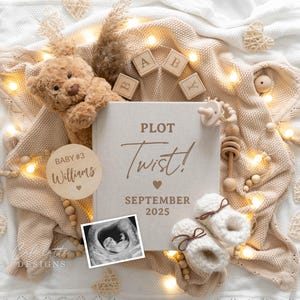 May include: A wooden sign with the text "PLOT Twist!" and "SEPTEMBER 2025" in brown lettering. A wooden circle with the text "BABY #3 Williams" is in the image. A teddy bear, wooden blocks, a baby rattle, and baby booties are also in the image.