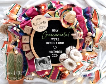 Può includere: Una lavagna nera con il testo "HOLY GUACAMOLE! WE'RE HAVING A BABY NOVEMBER 2024" circondata da una varietà di articoli per bambini, tra cui un cartello in legno con il testo "BABY Williams", un piccolo cactus, uno sonaglio di legno, un paio di scarpette di lana e una ghirlanda di luci.