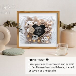 May include: A framed print with a white background and a black heart-shaped chalkboard with the text "We've been keeping a little secret" and the date "September 2024". The print also includes a white stuffed lamb, wooden blocks spelling "baby", and a small white baby bootie.