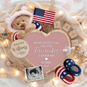 May include: A baby announcement with a teddy bear wearing a pink hood and patriotic accents. The announcement includes a pink heart-shaped sign with the text "WE ARE EXCITED TO SAY OUR LITTLE Firecracker IS ON HER WAY OCTOBER 2027". Also featured are baby shoes, blocks, and an ultrasound image.