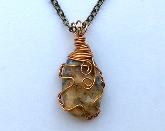 May include: A silver chain necklace with a brown and white agate stone pendant wrapped in copper wire.