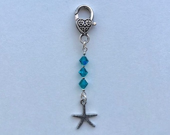 May include: A silver charm with a heart-shaped clasp and a blue crystal bead chain. A silver starfish charm hangs from the end of the chain.