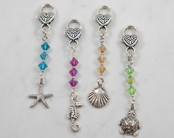 May include: Four silver charm bracelets with heart-shaped clasps and different colored crystal beads. Each charm features a different sea creature: a starfish, a seahorse, a seashell, and a turtle.