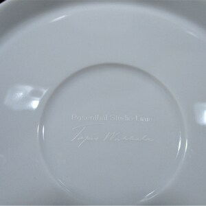 以下が含まれることがあります： 白のセラミックソーサーで、中央がくぼんでいます。「Rosenthal Studio Linie」と「Topio Miracle」の文字が表面にさりげなくエンボス加工されています。ソーサーは滑らかで光沢のある仕上がりです。