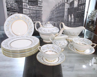 Könnte beinhalten: Ein komplettes weißes Porzellan-Teeservice mit goldenem Rand und zartem Blumenmuster. Das Set beinhaltet Teller, Tassen, Untertassen, eine Teekanne, einen Sahnekännchen und eine Sauciere.