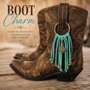 Puede incluir: Una bota vaquera de cuero marrón adornada con un dije de flecos de gamuza turquesa que incluye un anillo dorado, un colgante de metal en forma de diamante con una pequeña piedra turquesa y cuentas doradas. Texto: BOOT Charm, SLIDES ON. STANDS OUT. UNIVERSAL FIT FOR KIDS TO ADULTS.
