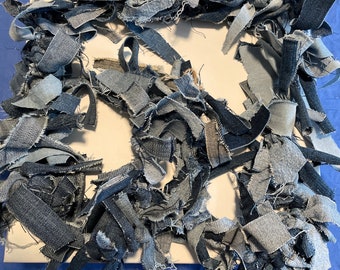 May include: A white canvas covered in blue denim scraps, creating a textured, abstract design.