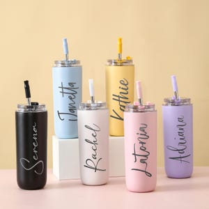 Puede incluir: Una colección de vasos aislados en varios colores pastel, cada uno con una pajita a juego y un nombre en escritura elegante. Los colores incluyen negro, azul claro, blanco, amarillo, rosa y morado. Los vasos están diseñados para bebidas frías.