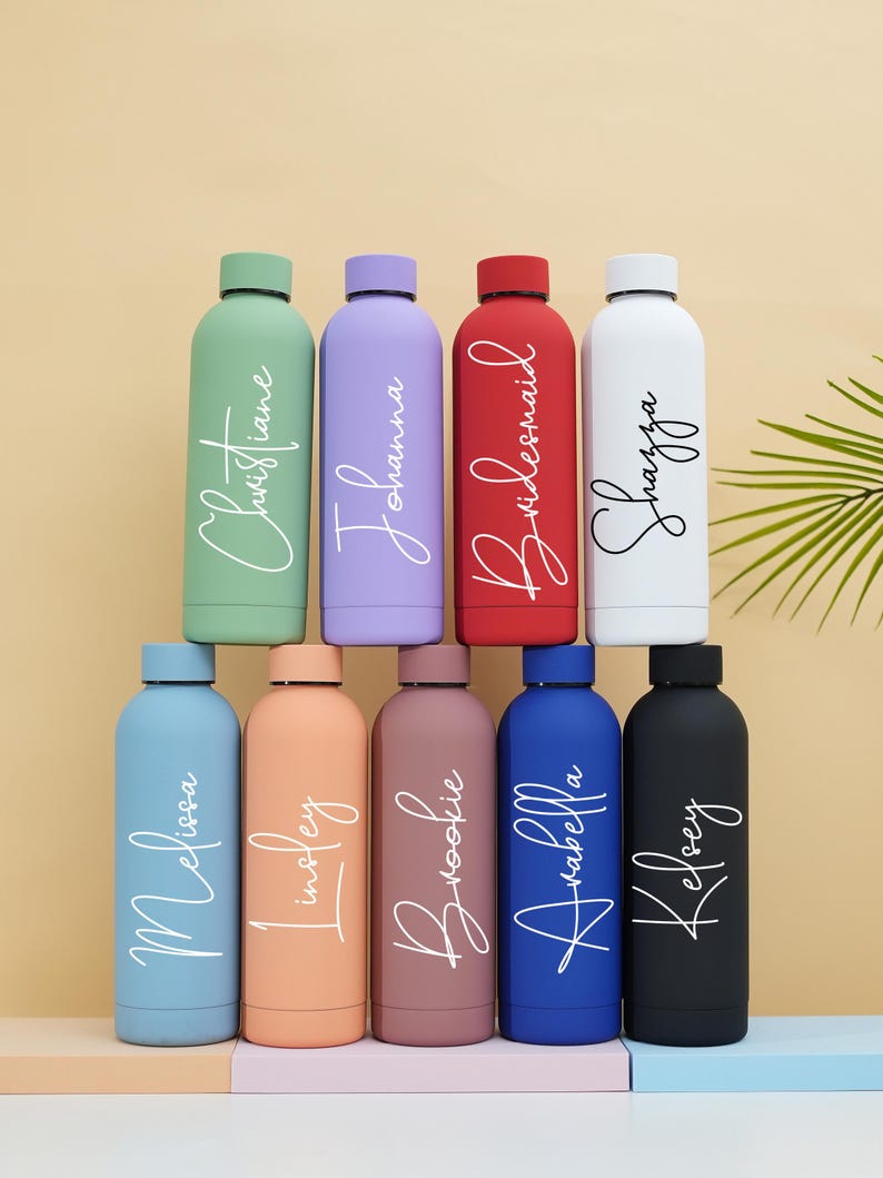 May include: Ten stainless steel water bottles in various colors with personalized names in white script. The bottles are arranged in two rows of five. The names on the bottles are:  Christiane, Johanna, Bridesmaid, Sharifa, Melissa,  insley, Brookie, Arabella, and Kelsey.