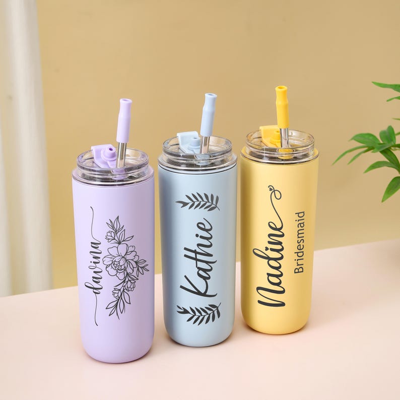 May include: Three personalized stainless steel tumblers with straws. One is lavender with a floral design and the name "Davina". The second is light blue with the name "Kathie". The third is yellow with the name "Nadine" and the word "Bridesmaid".