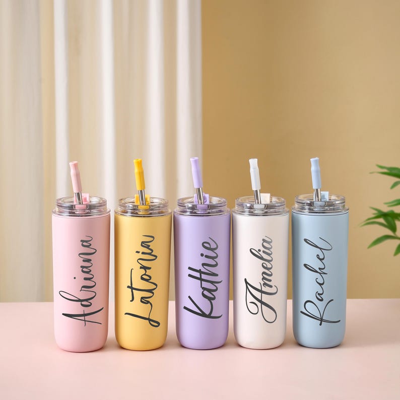 May include: Five pastel-colored stainless steel tumblers with lids and straws. Each tumbler is a different color: pink, yellow, purple, white, and blue. Each tumbler has a name in black script: Adriana, Latoria, Kathie, Amelia, and Rachel.