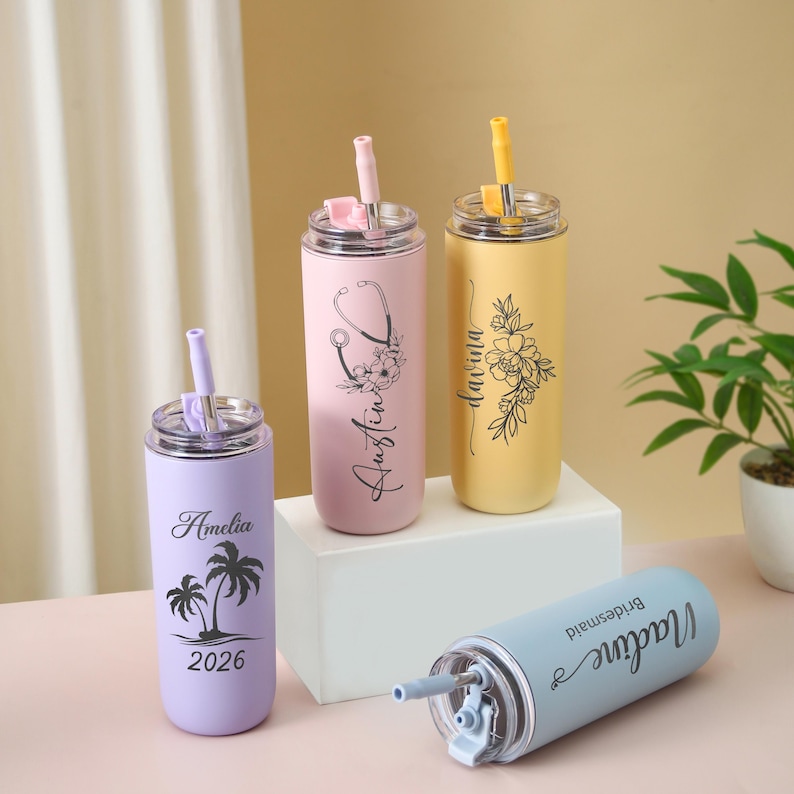 May include: Four personalized stainless steel tumblers in pastel colors. One lavender tumbler has a palm tree design and the name "Amelia" and the year "2026". A pink tumbler has a stethoscope design and the name "Austin". A yellow tumbler has a floral design and the name "Davina". A blue tumbler has the name "Madine" and the word "Bridesmaid".