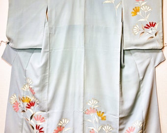 May include: A light blue kimono with floral embroidery in shades of pink, yellow, and red. The flowers are stylized and have a delicate, feminine feel.