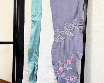 May include: A collection of four rectangular fabric panels draped vertically. The set includes a black panel, a white panel with subtle patterns, a textured turquoise panel, and a lavender panel featuring white floral embroidery with pink centers.