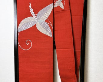 May include: A striking red kimono with intricate floral embroidery in white, silver, and pale blue. The design showcases a large, stylized flower with detailed patterns and a delicate, swirling vine. The kimono is displayed on a black rack.