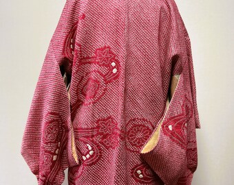 May include: A red and white patterned Japanese Hanten jacket with a floral design. The jacket is made of a soft, textured fabric and has a traditional Japanese style.