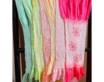 May include: A rainbow-colored fabric scarf with embroidered flowers. The scarf is made of a soft, sheer material and has a ruffled edge.