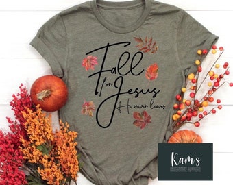 Könnte beinhalten: Ein grünes T-Shirt mit dem Text "Fall for Jesus He never leaves" in schwarzer Schrift. Der Text ist von Bildern von Herbstblättern in Orange-, Rot- und Gelbtönen umgeben.