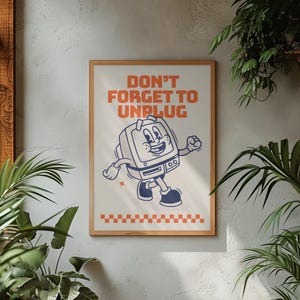 May include: A framed poster with the text "DON'T FORGET TO UNPLUG" in orange. The poster features a cartoon computer character with a smiling face, walking with a happy expression. The bottom has an orange and white checkered pattern.