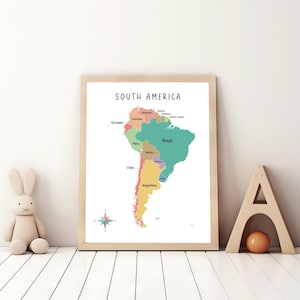 May include: A colorful map of South America with the countries labeled in black text. The map is framed in a light wood frame and is hanging on a white wall.