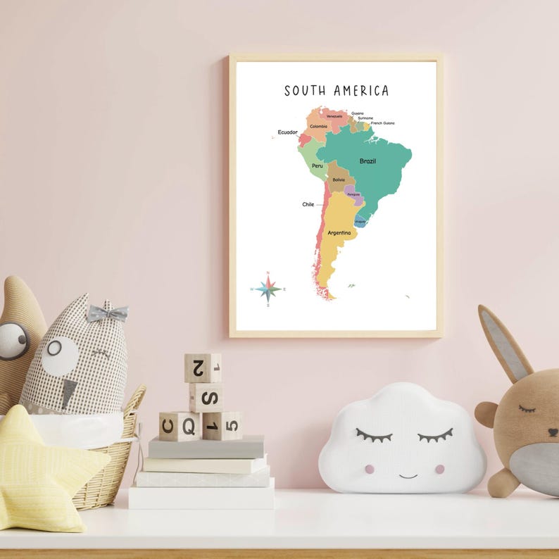 May include: A colorful map of South America with the countries labeled. The map is framed in a light wood frame and is hanging on a pink wall. There are toys and books on a white shelf below the map.