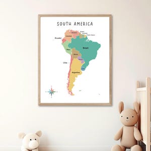 May include: A colorful map of South America with each country labeled. The map is framed in a light wood frame and is hanging on a white wall.