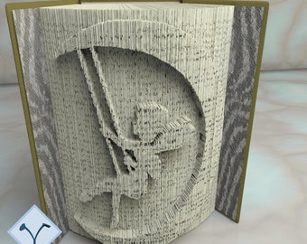 May include: An open book with a detailed design cut into the pages. Text includes "PATTERNS FOR 28 BOOK SIZES" and "16 IN CM + 12 IN INCHES". The book's pages are cut to form an image. The words "BASIC" and "METHOD I" are also visible.