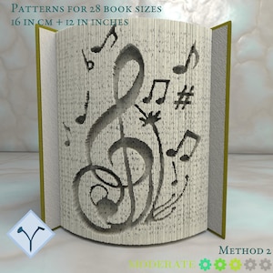 Puede incluir: Una escultura de libro con temática musical, con una gran clave de sol y notas musicales talladas en las páginas. El texto "PATTERNS FOR 28 BOOK SIZES 16 IN CM + 12 IN INCHES" es visible. El libro está abierto, con lomo verde.