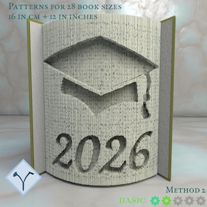 Może przedstawiać: Rzeźba książki z motywem czapki absolwenta i rokiem 2026 wyciętym w stronach. Tekst "PATTERNS FOR 28 BOOK SIZES 16 IN CM + 12 IN INCHES" znajduje się na górze. Książka jest otwarta, ukazując wycięty wzór.