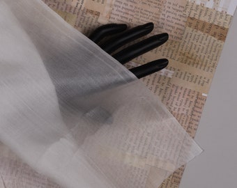 May include: A white sheer fabric with a smooth texture. The fabric is draped over a printed surface.